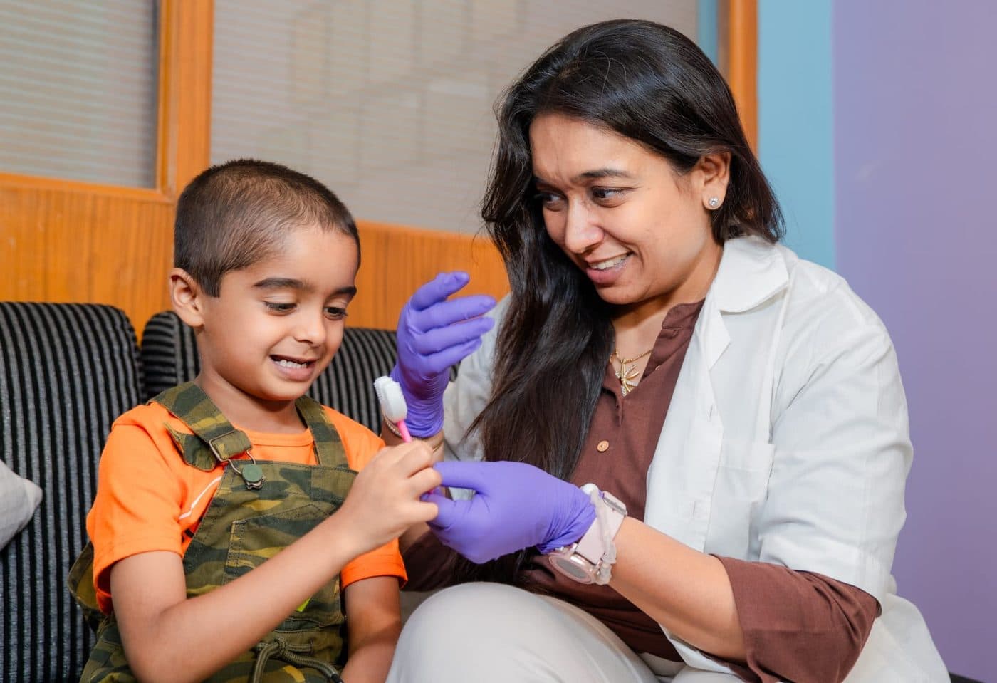 Dr Kavya Mathur showing a young boy how to brush, both of them laughing